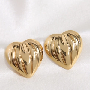 Detail of heart-shaped gold stainless steel earrings with textured pleated finish
