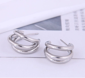 Détail macro de boucles d'oreilles en acier titane argenté au design multicouche
