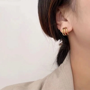 Détail de boucles d'oreilles multicouches en acier titane doré en forme de C sur modèle