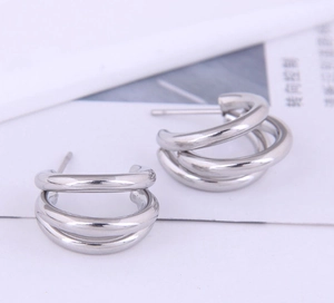 Gros plan sur des boucles d'oreilles à trois anneaux entrelacés en métal argenté poli