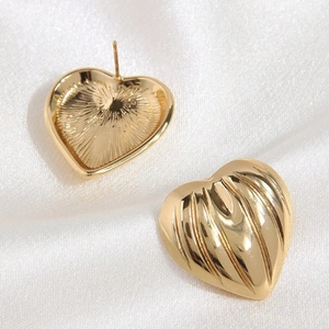 Chic gold heart stud earrings with radial striped texture on satin background