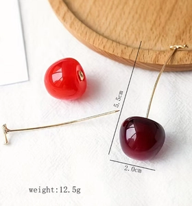 Détail des boucles d'oreilles cerise montrant la longueur de 5,5cm et les perles