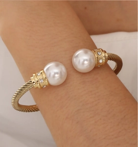 Detailed close-up of golden spiral cuff bracelet with large pearls and sparkling crystals