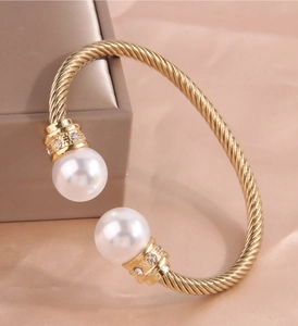 Detail of gold twisted cable cuff bracelet with large white pearls and sparkling zircon