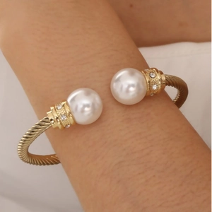 Elegant gold twisted open bangle featuring two large pearls and sparkling rhinestone accents