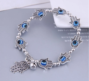 Detail view of bohemian beaded bracelet featuring silver Hamsa Hand and Evil Eye charms