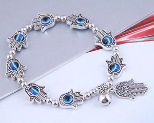 Detail of Hamsa Hand and Evil Eye beads on a polished silver metal beaded bracelet