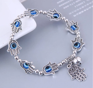 Detailed close-up of Hamsa beads and blue evil eye charms on a silver-plated bracelet