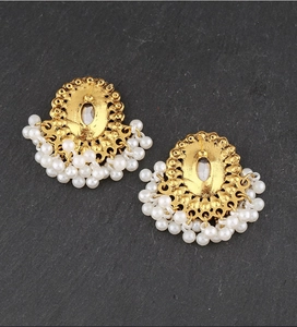 Dettaglio di orecchini vintage dorati con pendenti di perle finte bianche
