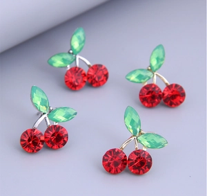 Detailed view of cherry earrings with faceted red stones and green gem leaves