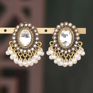 Dettaglio di orecchini vintage dorati con cristallo ovale e nappe di perle bianche