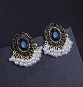 Dettaglio di orecchini vintage con pietre blu e nappine di perle bianche lucide