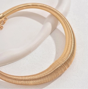 Nahaufnahme eines goldenen Metall-Chokers mit Federstruktur und verstellbarer Kette