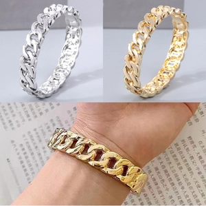 Dettaglio di bracciali rigidi a catena cubana intrecciata in finitura oro e argento
