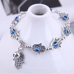 Silver Evil Eye Hamsa Hand bracelet with small bells on a white display stand