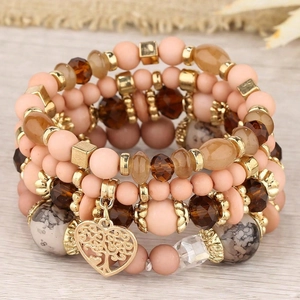 Détail de bracelet multicouche en perles avec pendentif cœur arbre de vie sur bois