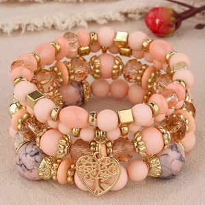 Gros plan d'un bracelet multicouche en perles pêche avec pendentif cœur arbre de vie