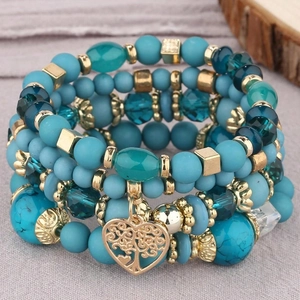 Détail macro du bracelet à plusieurs rangs avec pierres turquoise et breloque cœur dorée