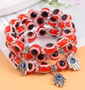 Detailed close-up of triple-layer red Evil Eye beaded bracelets with Hamsa Hand pendants