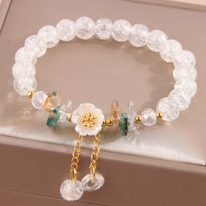 Elegant beaded bracelet with floral charms and crystals on a soft display base