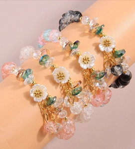 Close-up of beaded bracelet set with pink floral charms and crushed stone textures