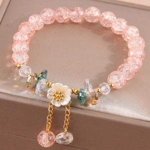 Elegant floral beaded bracelet with pink crackle glass and shell flower charms on a jewelry box
