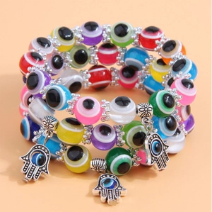 Detail of bohemian layered elastic evil eye bracelets with hamsa hand charms and beads