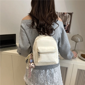 Mini zaino in pelle color crema da donna con ciondolo di peluche in ambiente lifestyle