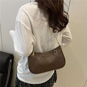 Brown litchi texture crossbody bag with gold chain strap worn by a female model