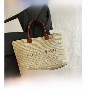 Close-up of a large woven tote bag with leather handles on a white textured background