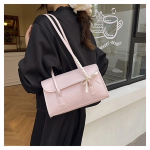 Detail showing a light pink baguette bag with cream satin bow on double shoulder straps