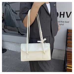 Detail of elegant off-white bow shoulder bag with slim straps in a lifestyle setting