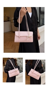 Détail du sac baguette rose avec des rubans blancs portés avec une robe noire