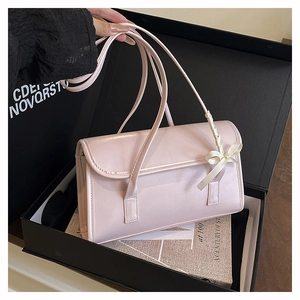 Close-up of pink ribbon bow detail on glossy leather shoulder bag in a gift box