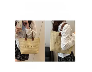 Detail showing the large beige woven tote bag with brown leather handles and text