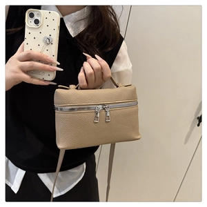Close-up of beige lychee grain leather vanity bag with double metal zippers and top handle