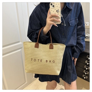 Mirror selfie showing a woman with a large beige straw tote bag and brown leather handles