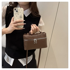 Detail view of brown pebbled leather handbag with silver dual zippers and top handle