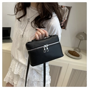 Detail of black lychee grain leather mini bag with silver hardware and dual zippers