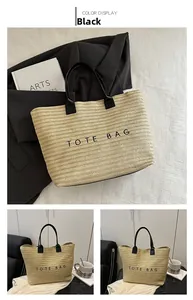 Detailed view of beige straw tote bag with black leather handles and printed text