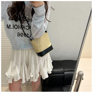 Detail of summer woven bucket bag with beige straw texture and black leather base
