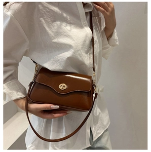 Detail of caramel brown leather shoulder bag with elegant golden metallic twist lock