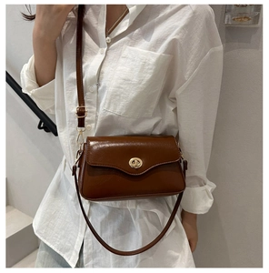 Detailed view of dark brown glossy leather crossbody bag with a gold metal clasp closure