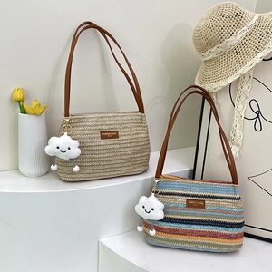 Large straw tote bag with brown leather straps and cloud charm in a summer setting
