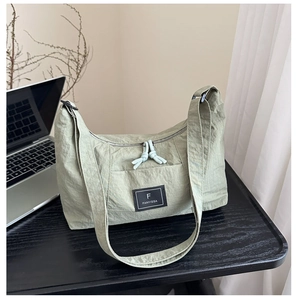 Detailed close-up of mint green pleated nylon shoulder bag with a woven brand label