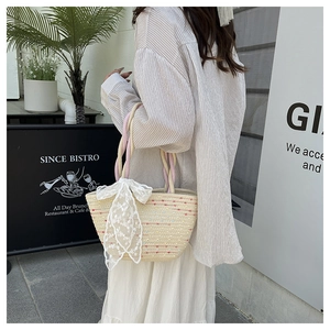 Close-up of handmade woven straw bag with colorful texture and white lace bow detail