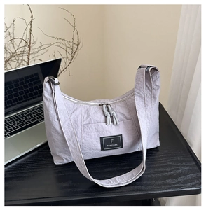 Detail of light purple nylon shoulder bag showing wrinkled texture and dual zipper closure