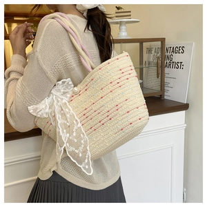 Detail of woven straw tote bag featuring white lace bow, pearl clasp and pink rope handle
