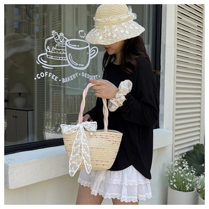Detail of woven straw handbag with a large white lace bow and elegant pearl buckle