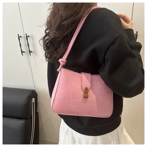 Detail of pink croc-embossed underarm bag featuring a vintage gold clasp and knotted strap